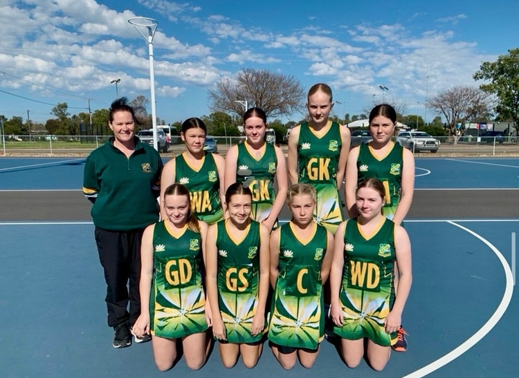 Photograph of students dressed in Wee Waa High School netball uniforms standing outside on netball courts with teacher dressed in Wee Waa High School jumper