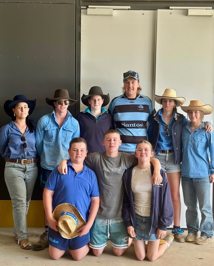 Photograph of students smiling with arms around each other wearing blue outfits for Day for Dolly fundraiser