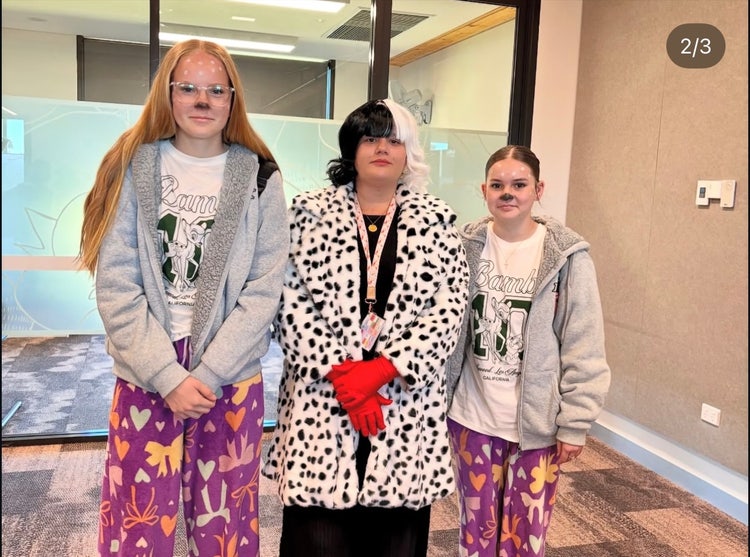 Photograph of students dressed up as dalmatian dogs and staff member dressed up as Cruella DeVille character for book week standing inside classroom
