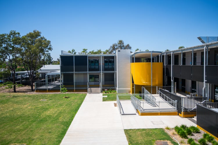 Photograph of Wee Waa High School quadrangle with building, concrete paths, and grassed area under blue sky